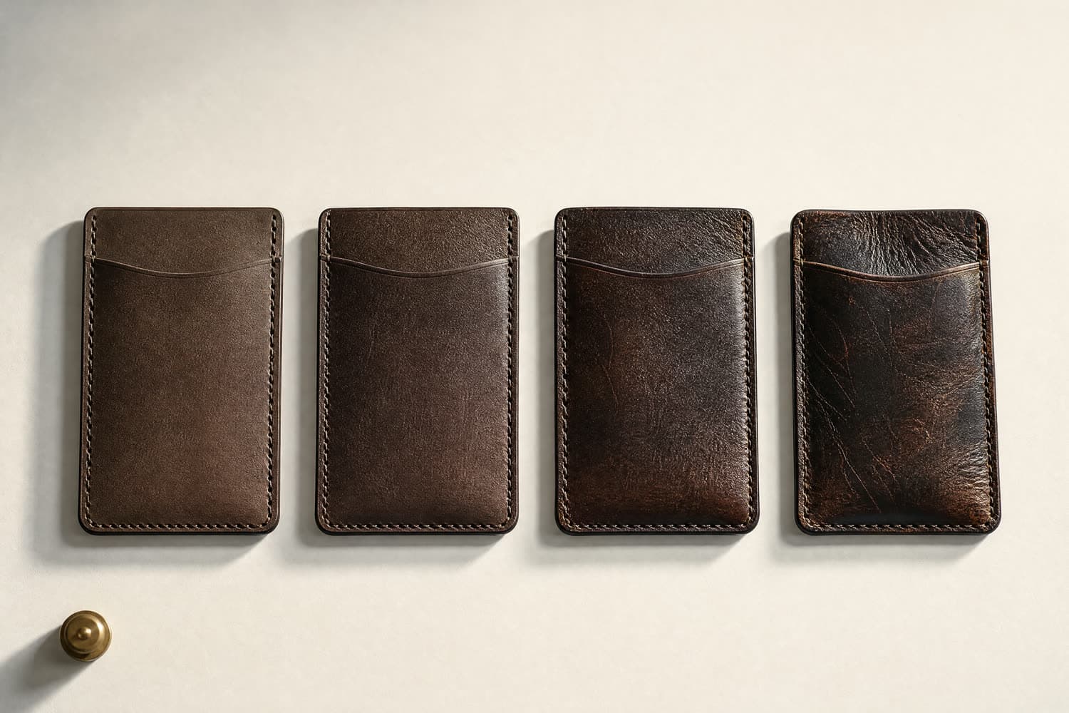 Four identical card holders progressing from pale and stiff to deeply darkened and burnished